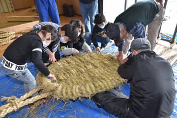 大人がわらの編み込みを行い、子どもたちがはさみで表面のけば取りなどを行った=常陸太田市松栄町