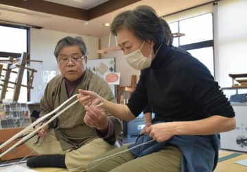 県本場結城紬織物協同組合の小島章理事長(左)から下拵えの作業を教わる受講者=結城市結城