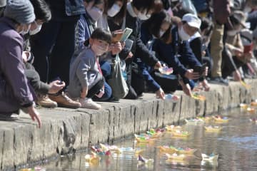 折り雛を乗せた舟を山口川に流す人たち=桜川市真壁町飯塚