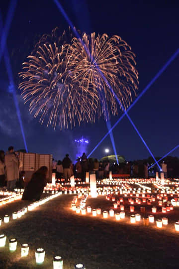 キャンドルの灯りの中、打ち上がる花火を見る来園者ら=4日午後7時54分、水戸市常磐町