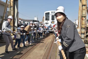 列車を相手に綱引きに臨む野口啓代さん(右手前)と参加者=龍ケ崎市内