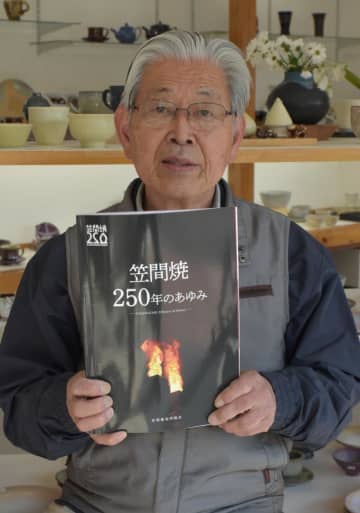 「笠間焼　250年のあゆみ」を手にする大津廣司理事長=笠間市笠間