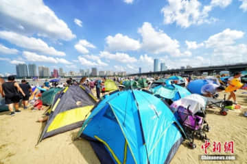 一線都市と二線都市では、若者が仕事の合間にキャンプ、サイクリング、ペットなど「ゆとりあるライフスタイル」を通じてストレスを解消している。写真はハルビン市の海水浴場。