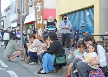 歩行者天国となった路肩に腰を下ろし、そばを味わうひといち朝市の来場者