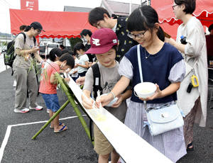 白河ラーメンを箸ですくい上げる参加者