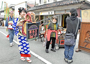 派手な衣装と軽快な音楽で会場を盛り上げる「チンドンうぐいす宣伝社」＝15日午後、喜多方市・レトロ横丁商店街