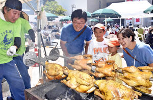 川俣シャモの丸焼きの実演販売に見入る来場者＝川俣町中央公民館