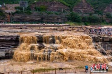 黄河壺口瀑布では雨が降った影響で1秒当たりの流量が700立方メートルに増加し、黄色い水が勢いよく流れ落ち、圧巻の光景が広がっている。