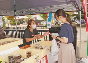 駐車場の一角で接客する出店事業者の関係者。１１月まで各事業者が多様な飲食物、品々を売り出す＝１３日、北上市本通り・北上信用金庫本店