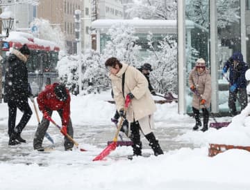 スコップを手に除雪作業に追われる人たち＝12月22日午前9時ごろ、新潟市中央区西堀通6