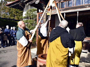 つき上げた餅を高く掲げる僧侶