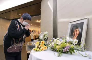 小澤征爾さんの笑顔の写真が飾られた献花台を訪れ、別れを惜しむ女性=10日午後、水戸芸術館