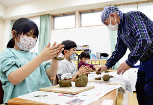 半谷さん（右）の指導で、粘土をこねて陶器の形を作る子どもたち＝19日午後、浪江町