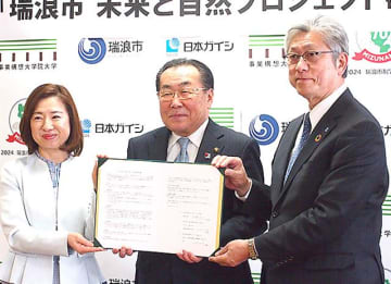 協定書を手にする（左から）田中学長、水野市長、山田取締役