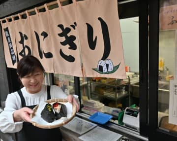 ふっくら亭の前でおにぎりを手にする木村成美総支配人