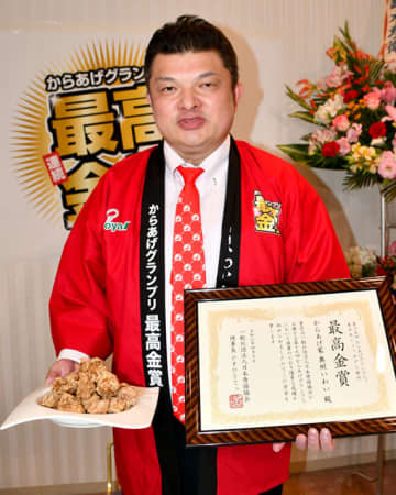 からあげＧＰの東日本しょうゆダレ部門最高金賞の賞状と製品を掲げる小山常務
