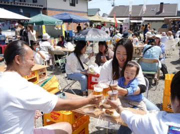 出店が並ぶ会場で、飲食を楽しむ来場者