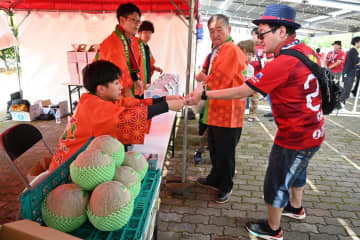 鉾田市産のメロンを買い求める鹿島のサポーター(右)=鹿嶋市神向寺