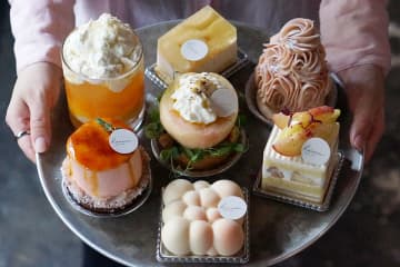 写真上から時計回りに「桃のレアチーズケーキ」、「モモンブラン」、「桃のショートケーキ」、「ニュアージュペッシュ」、「桃のシブースト」、「ピーチティーヨーグルト」、写真中央「桃のタルト」