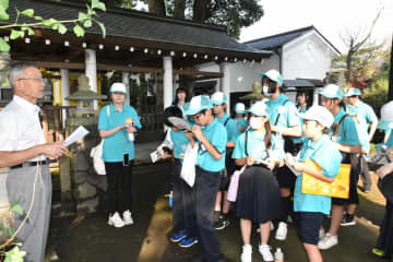 回天神社代表役員の羽部道紀さん(左)の説明に聞き入る福井県敦賀市の児童ら=水戸市松本町