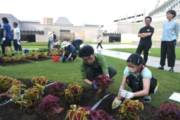 参加者と花の苗を植えるアート・ユニットの小林直人さん(手前左)=水戸市五軒町