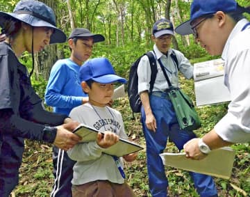 森林管理署の職員（右）から樹木の特徴について説明を受ける親子ら＝福島市