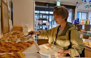 復刻パンのコーヒーロールを取る来店客。市民らに親しまれる味を提供する