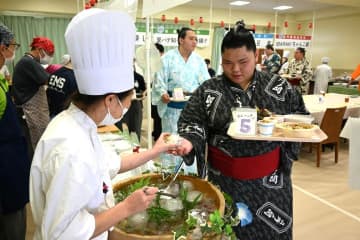 専門学生が調理した「推しメシ」を受け取る力士ら=牛久市ひたち野東