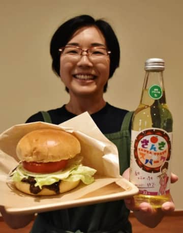 目玉商品「くじらバーガー」と「さんさスパーク」をアピールする級木美子代表