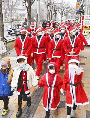 サンタクロース姿で街中をパレードする参加者