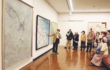 西藤さん（左）の解説を聞きながら作品を鑑賞する来場者＝県民会館